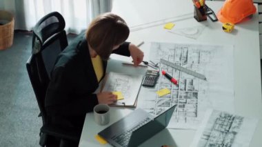 Zeki iş kadınlarının yürüyüşü ve ev tasarımı. Mimar mühendisinin güvenlik miğferi ve ev modeliyle birlikte binanın planına ve yapısına baktığı hava görüntüsü. Hizalama.