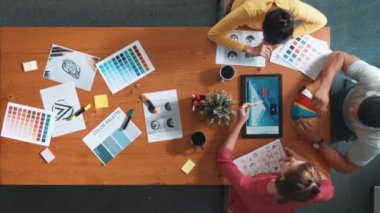 Proje yöneticisi renk paletleri seçerken tasarımcının tablete baktığı yukarıdan aşağıya hava görüntüsü. Profesyonel grafik tasarımının en üst görüntüsü ve logoya bakın. Yetenekli ekip grafikleri seçiyor. Sempozyum.