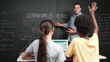Afrikalı çocuk akıllı öğretmene kodlama programını sormak için elini kaldırdı. Akıllı öğrenci, STEM teknoloji sınıfında dizüstü bilgisayar ekranı görüntülerken soru sormak, oy vermek, gönüllü olmak için elini kaldırdı. Öğretim