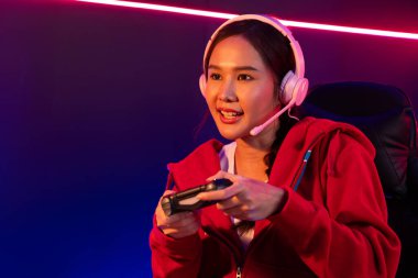 joystick 'li güzel Asyalı kız flamasının sunucu kanalı kulaklık takarak online oyun oynuyor Pastel renkli kulaklıklar takarak izleyicilerle çevrimiçi konuşuyor. Esport yetenekli takım oyuncuları neon odada. Taktik.