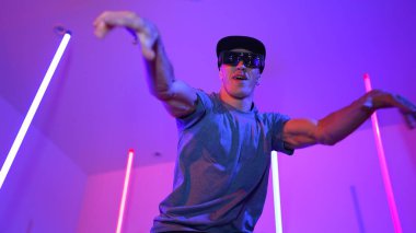 Beyaz dansçının gösterişli gözlükler taktığı ve break dans yaptığı alçak açılı kamera. Çekici adam kendinden emin bir şekilde kameraya bakarken enerjik bir performans ve hareket gösterdi. Mutluluk.