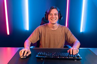 Kazanmak için çevrimiçi oyun oynayan akıllı flama makinesinin sunucu kanalı, neon ışıklı odada seçilen takım yarışması için izleyicilerle birlikte canlı yayında canlı yayında kulaklık takıyor. Bireysel.