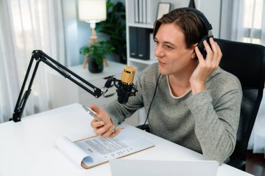 Sunucu kanalı, gülümseyen akıllı yayıncı kaydı, senaryosu ve akıllı telefonuyla sosyal medyada sohbet programı, kulaklık takarak modern ev stüdyosundaki video flamalarını kaydediyor. Bireysel.