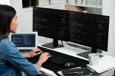 İnternet sitesi uygulamasının kodlama verileriyle birlikte online bilgi yazarak kot gömlek giyen genç Asyalı geliştirici. Güvenlik analizi ile çevrili iki ekran. Taktik.