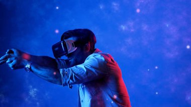 Yetenekli oyuncular silah olarak el ele tutuşup VR gözlük takıp atış oyunu oynayarak metaevrene girebiliyor. Çekici erkek model mavi arka planda dururken hareket ediyor ve oyuncuyu hedef alıyor. Aygıt.