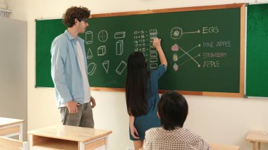 Genç Asyalı kız sınıfta dururken tahtada matematik formülü yazıyor. Çekici ilköğretim öğrencisi matematik dersinde çalışırken ya da soru cevap verirken. Eğitim konsepti. Pedagoji.