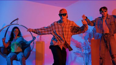 Stüdyoda gündelik kıyafetleri olan çok kültürlü bir arkadaş tezahürat yaparken mutlu hipster break dansları. Profesyonel sokak dansçısı hip hop ritmi ya da neon veya kurşun ışıkla kafiyeli bir şarkı söyler. Mutluluk.