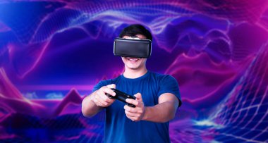 Profesyonel oyuncu, elinde pembe ve mor gradyan arka planda joystick tutarken VR kulaklık takıyor. Gelişigüzel giyinen yetenekli bir oyuncu ve arka planda artırılmış gerçeklik teknolojisi kullanıyor. Yaratıcılık.