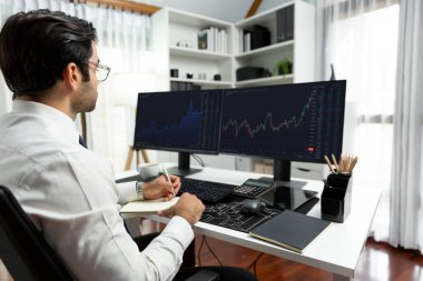 Akıllı tüccar işadamı, modern merkez ofisindeki araştırma pazarında en yüksek kârlı finansal teknolojiye yatırım yaparak bilgisayar üzerinde iki dinamik borsa yatırım ekranını analiz ediyor. Tahmin et..