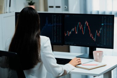 Modern ofisteki borsa grafiğinin kârını analiz etmek için bilgisayara bakan genç ve güzel Asyalı bir iş kadını. Finans sektöründe refah güvenliğine yüksek kâr yatırımı kavramı. Taktik.