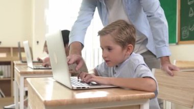 Çeşitli öğrenciler yapay zeka yazılımı kullanırken, Kafkas öğretmeni enerjik çocuğa kodlama konusunda yardım ediyor. Çocuklar oturma ve programlama sistemi. Sevimli bir öğrenci şifreyi öğreniyor. Pedagoji.