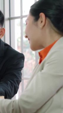 İki iş adamı toplantı odasında proje stratejisi hakkında konuşuyor. İş adamı, mali veri raporu hakkında sohbet ve tavsiyelerde bulunurken, modern işyerindeki iş arkadaşıyla proje planlamasını tartıştı.