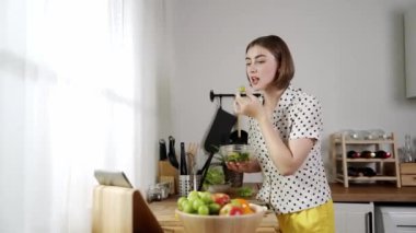 Mutlu genç anne mutfakta dururken salata kasesine sebze koydu. Çekici beyaz bir kadın yemek pişirmekten ve sabah taze organik yemek yapmaktan ya da ev yemeği yapmaktan zevk alır. Pedagoji.