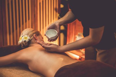 Masör elleri kadının sırtına aroma yağı döküyor. Masözler lüks otellerdeki kaplıca salonundaki müşteriler için yağ masajı prosedürü hazırlıyorlar. Aroma yağı vücut masajı konsepti. Sessiz.
