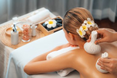 Sıcak bitkisel top spa masaj vücut tedavisi, masör kadın vücuduna nazikçe şifalı bitki torbası bastırıyor. Aromaterapi dinlenme sükuneti ve sükuneti kaplıca salonundaki atmosferi aydınlatıyor. Sessiz.