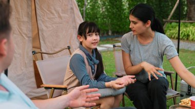 Aile hep birlikte bahçedeki kampta oturup yemek yiyor. Sevimli ebeveynler, genç nesil arasında iletişim kurmak ve zaman geçirmek için açık hava kamp faaliyetlerini kullanırlar. Uyumsuzluk.