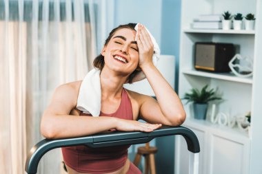 Spor ve atletik bir kadın, evdeki fiziğe ve sağlıklı spor yaşam tarzına uygun vücut egzersizi sırasında koşu bandında koşuyor. Gaiety evde egzersiz eğitimi.