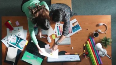 Tasarımcı yazma fikri ekrana bakarken proje yöneticisinin üst görünümü. Akıllı iş adamlarını kapat ve tasarımcı palete bakarken logo tasarımı fikrini açıkla. Sempozyum.