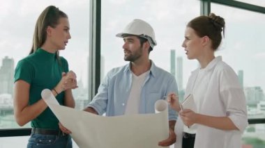 Profesyonel mimar mühendis ekibi konuşuyor, paylaşıyor, tasarım hakkında beyin fırtınası yapıyor. Yönetici planı dinlerken genç mimar plan yapıyor. İzleme