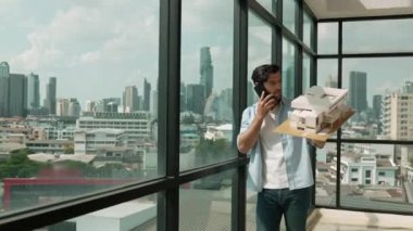 Gülümseyen Kafkasyalı mühendis ev modelini sağa sola çeviriyor ve iş arkadaşına telefon ederken hata noktasını kontrol ediyor. Profesyonel yönetici teftiş, kontrol, mimari modele bakmak. İzleme