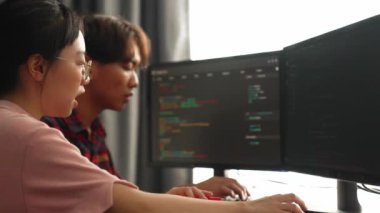 Yavaş çekim arkası yazılım geliştirici mühendisi bilgisayar programlama için birlikte çalışarak hata ayıklama kodunu çözüyor, ofiste monitörde karmaşık algoritmaları çözüyor. Filizlenen