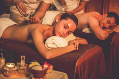 Masör elleri çift müşterinin sırtına aroma yağı döküyor. Masözler lüks otellerdeki kaplıca salonundaki müşteriler için yağ masajı prosedürü hazırlıyorlar. Aroma yağı vücut masajı konsepti. Sessiz.