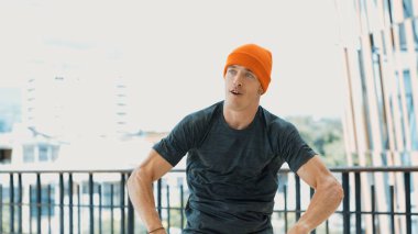 Enerjik hipster, koridorda kendine güvenen bir şekilde poz verirken kameraya bakıyor. Profesyonel koreografın yakın plan portresi sokak dansı yapıyor. Break dans. Açık hava sporu 2024. Hiphop.