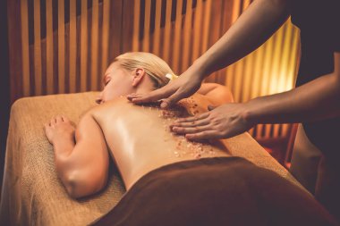 Lüks spa salonlarında sıcak mum ışığında cilt bakımı yaptıran kadın müşteri. Sağlık Spa vücut fırçasında tuz temizleme güzellik tedavisi. Sessiz.