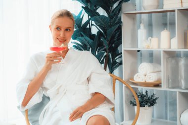 Güzellik ya da vücut bakımı güzellik salonu yaşam tarzı konsepti. Bornoz giyen bir kadın lüks otel kaplıcalarında ya da tatil odasında içkiyle rahatlıyor. Tatil ve boş zaman rahatlığı. Sessiz.