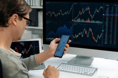 Akıllı borsa yatırımcıları ekranda akıllı telefon ile piyasa borsasını işaret ederek dizüstü bilgisayarın yanı sıra en yüksek dinamik yatırım oranını göstererek, modern işyerindeki veri planlamasına odaklanıyorlar. Bireysel.