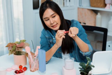 Genç, güzel Asyalı kozmetik makyaj ruju matte pastel rengini modern odadaki sosyal medyada kol testi tanıtımında en çok satanlar listesinde gösteriyor. Taktik.