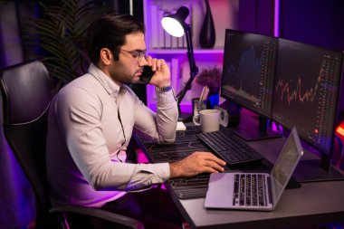 Tüccar akıllı işadamı komisyoncuyu ya da ortağını arıyor, modern evde kârlı bir finans teknolojisi olan neon aydınlatma ofisindeki bilgisayardaki dinamik borsa yatırımlarını analiz ediyor. Tahmin et..