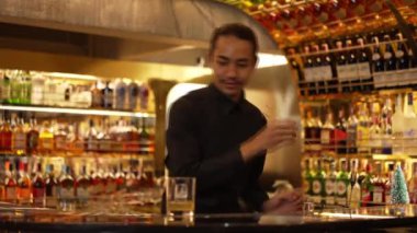 Zeki Asyalı barmen, bardakta karıştırılmış alkol şurubunu buzla karıştırıyor. Lüks gece kulübünde gece hayatı karışımı sergilenen özel bir içecek. Vinosity.