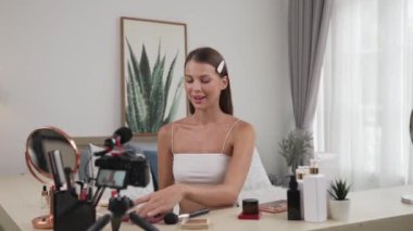 Genç kadın canlı yayına başlıyor. Sosyal medya için güzellik ve kozmetik video içeriği. Güzellik blogcusu kameraya gülümserken seyircilere ve takipçilere güzellik bakımını gösteriyor. Düzenle