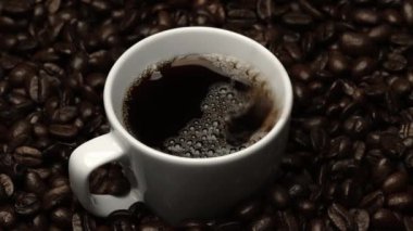 Kahve çekirdeğini yaklaştır ve kahve çekirdeği yığınıyla birlikte sıcak espresso 'ya bırak. Makro taze kavrulmuş fasulye aromatik dumanla bardağa düşüyor. Ağır çekim. Organik kahve tohumu kavramı. Geliştirilebilir.