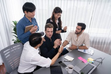 Çeşitli ofis çalışanları stratejik iş pazarlama toplantısı üzerine anlaşma yaptıktan sonra el sıkışıyor. Takım çalışması ve olumlu tutum verimli ve destekleyici bir iş yeri yaratır. Tedbirli