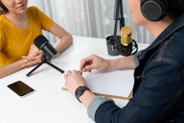 Gülümseyen radyo etkili sunucusu kulaklık takıyor kadın konuşmacı ile röportaj yapıyor sosyal medya internet sitesinden dinleyicilere bilgi paylaşıyor stüdyo kaydında sabah canlı yayın kanalı. İnfobahn.
