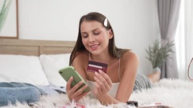 Genç bir kadın kredi kartıyla ödemek için internet üzerinden ödeme uygulaması ve dijital cüzdan kullanıyor. Mobil internet üzerinden alışveriş ve modern alımlar. Düzenle