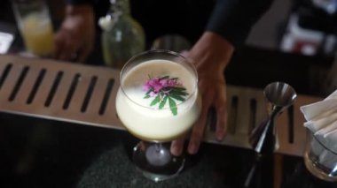 Tutkulu meyveli kokteyl bardağındaki barmen gece hayatı karışımı lüks gece kulübünde özel taze, süslenmiş pembe çiçek pürüzsüz köpük servis ediyor. Vinosity.