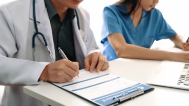 Hastane masasında birlikte çalışan ve tıbbi tedavi planlayan çeşitli profesyonel sağlık görevlileri. Takım çalışması başarılı hastalıklara ve hastalıklara yol açar. Ağır çekim. Katı.