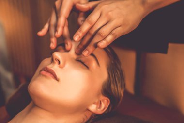 Beyaz kadın stres önleyici kafa masajı yapmaktan ve lüks otel veya otelde sıcak mum ışığında yüz güzelliği eğlencesi yapmaktan zevk alıyor. Sessiz.