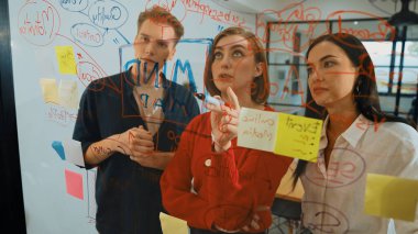 Genç yaratıcı şirket kurma ekibi fikir üretme ve sorunları renkli yapışkan notlar ve modern toplantı odasındaki zihin haritasını kullanarak çözme konusunda fikir üretiyor. Tartışıyoruz, birlikte çalışıyoruz. Tertemiz..