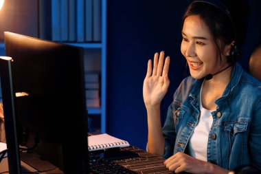 Sunucu kanalı Asyalı etkileyicisi canlı yayında konuşuyor. Sosyal medyada kulaklık takıyor, bilgisayar kaydı yapıyor, dinleyicileri selamlıyor ve Neon Modern Stüdyoları 'nda online olarak koçluk yapıyor. Taktik.