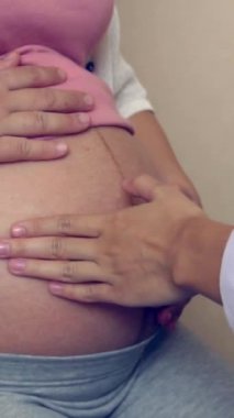 Mutlu hamile kadın, jinekolog doktoru hastanede ya da klinikte hamilelik danışmanlığı için ziyaret ediyor. Doktor, bebek ve anne sağlığı kontrolü için hamile karnı muayene ediyor. Jinekoloji konsepti.