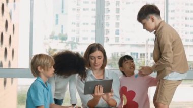 Bir grup öğrenciye çevrimiçi ders verirken elinde tablet tutan akıllı öğretmen. Yetenekli eğitmen mühendislik derslerini anlatırken genç öğrenci oturuyor ve sunumu dinliyor. Etkinlik.