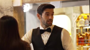 Yakışıklı, güler yüzlü bir barmen arkadaş, VIP müşterilerine içki listesi öneriyor. İçki tezgahı lüks, profesyonel barmen kostümü içinde harika bir ilk izlenim bırakıyor. Vinosity.