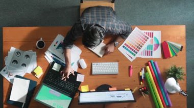 Akıllı iş adamının logo grafiği tasarlarken renk paletleri seçmesinin üst görünümü. Profesyonel iç mimar tasarımının hava görünümü ve renk paletleri kullanarak renk temasını seçin. Sempozyum.