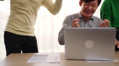 Yavaş çekim heyecanlı ve mutlu yaratıcı iş adamları grubu toplantı masasında başarılarını kutluyor. Etrafta dokümanlar ve dizüstü bilgisayarlar var. Yaratıcı iş başarısı kavramı. Değiştirilmiş