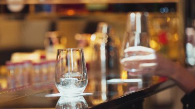 Yakından bir müşteri eli cin fizz ya da tonik ile Bokeh 'in sıcak gece kulübünün atmosferinde lüks bir bar manzarasında. Geceleri arkadaşlarla ya da barlarda ya da restoranlarda bir çiftle yaşam tarzı. Vinosity.