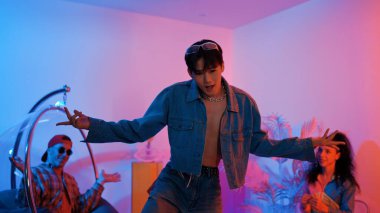 Çok kültürlü bir arkadaş kürsüde otururken Asyalı yetenekli bir dansçı modern müziğe geçiyor. Profesyonel dansçı, hipster takımı tezahürat yaparken ve desteklerken enerjik adımlar atıyor. Mutluluk.